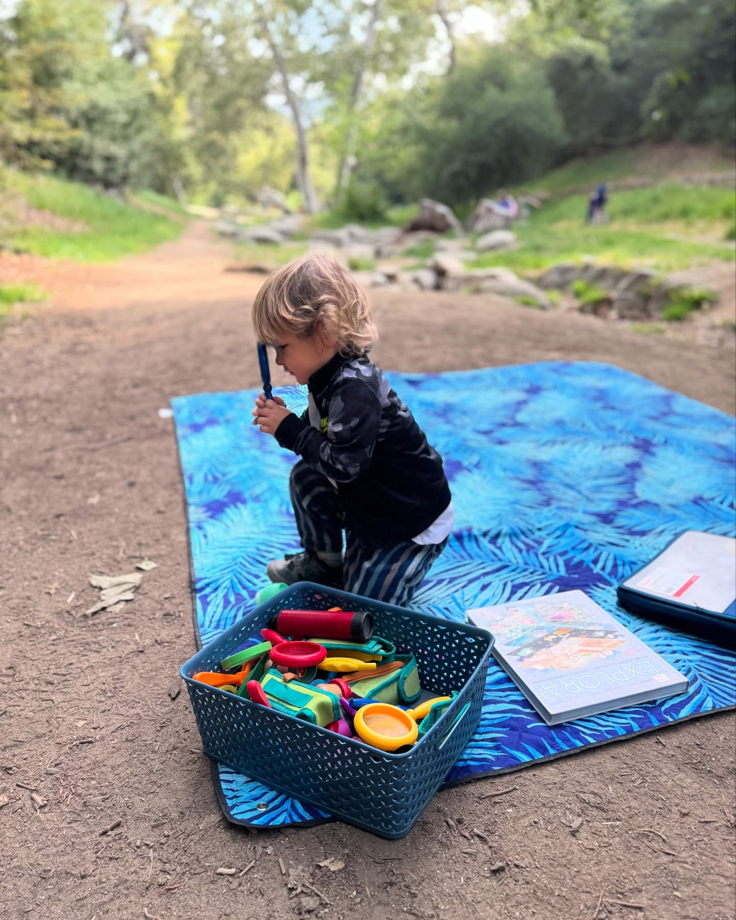 child on blanket with basket of materials for exploring